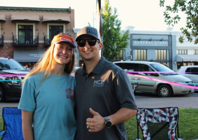 a man and woman at the park with chairs and cars and buildings behind them