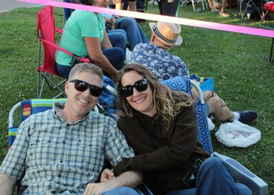 A man and woman sitting in lawn chairs at the park with a grassy background