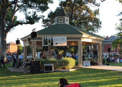 a green gazebo with people surrounding and a band playing inside