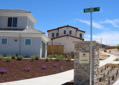 Two houses side by side with a street sign in front and a sign for River Oaks Manor
