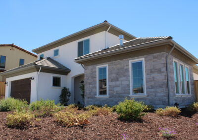 A large house with a yard, bushes, and mulch in front