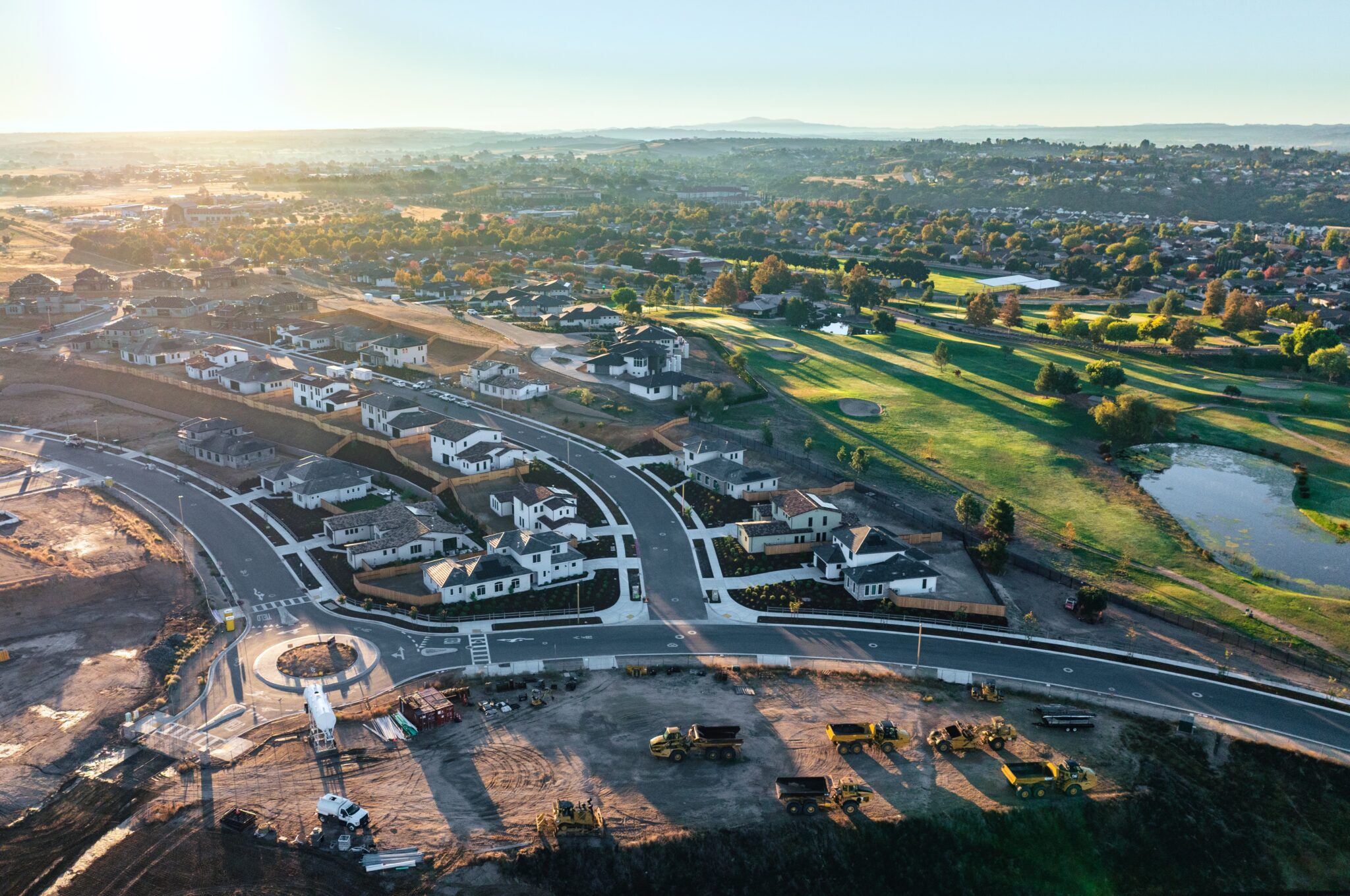 The Reserve at River Oaks Houses lined up along a street and roundabout with a golf course nearby