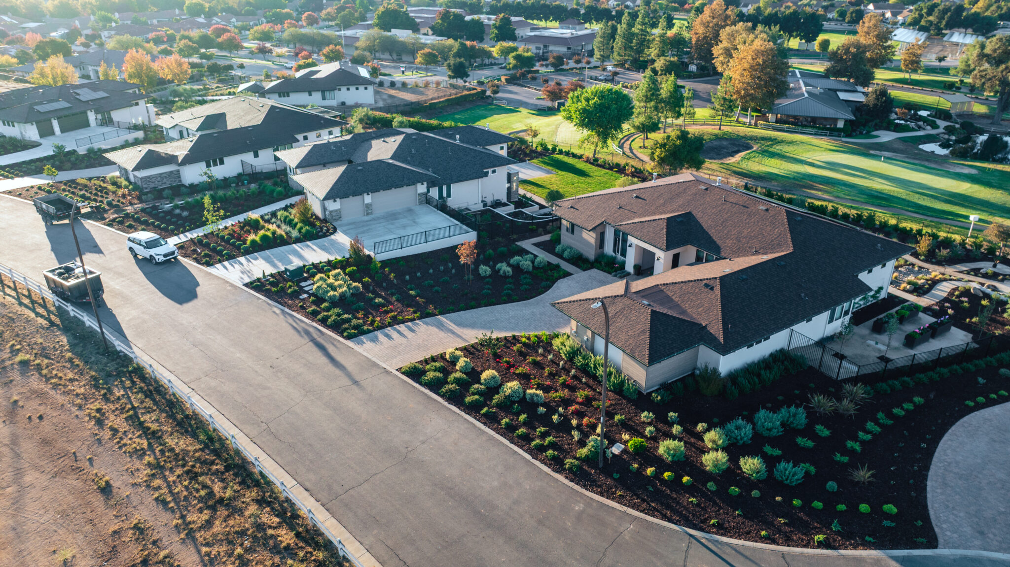 Houses lined up on a street with green golf course grass behind them and dirt in front at the Reserve at River Oaks