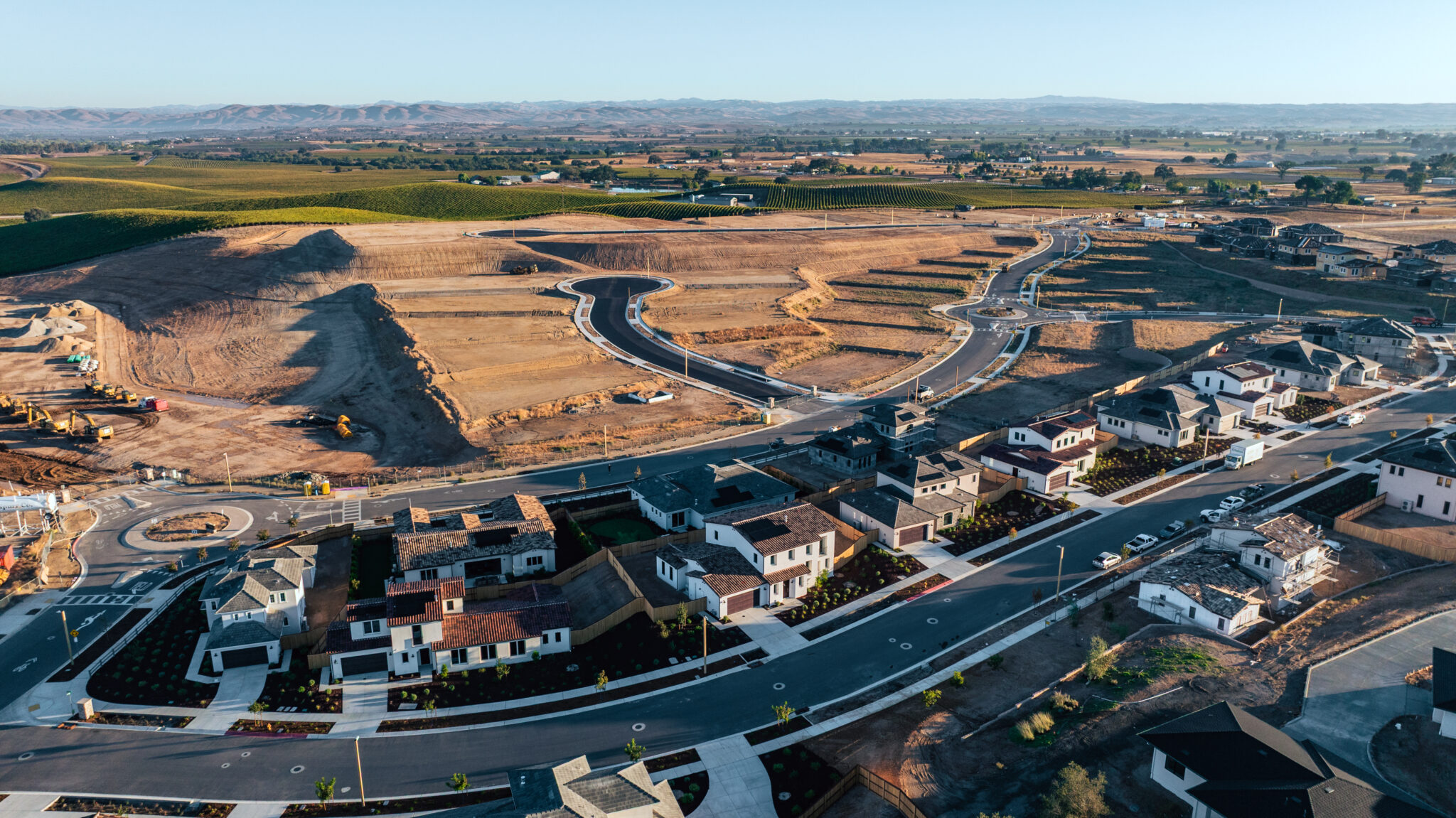 The Reserve at River Oaks in Paso Robles from an aerial angle showing a row of houses and a field of undeveloped land behind it