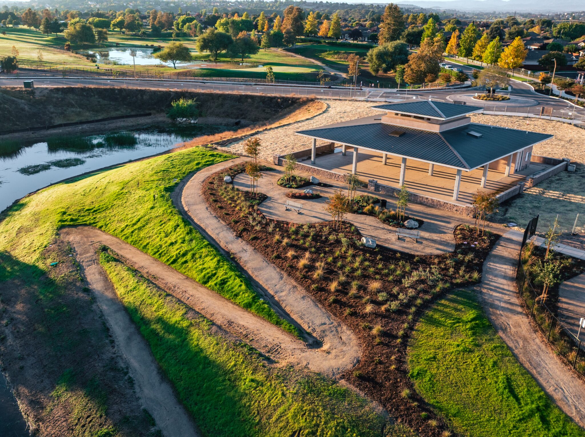 River Oaks Clubhouse on a hill with green grass and a winding path, surrounded by a pond
