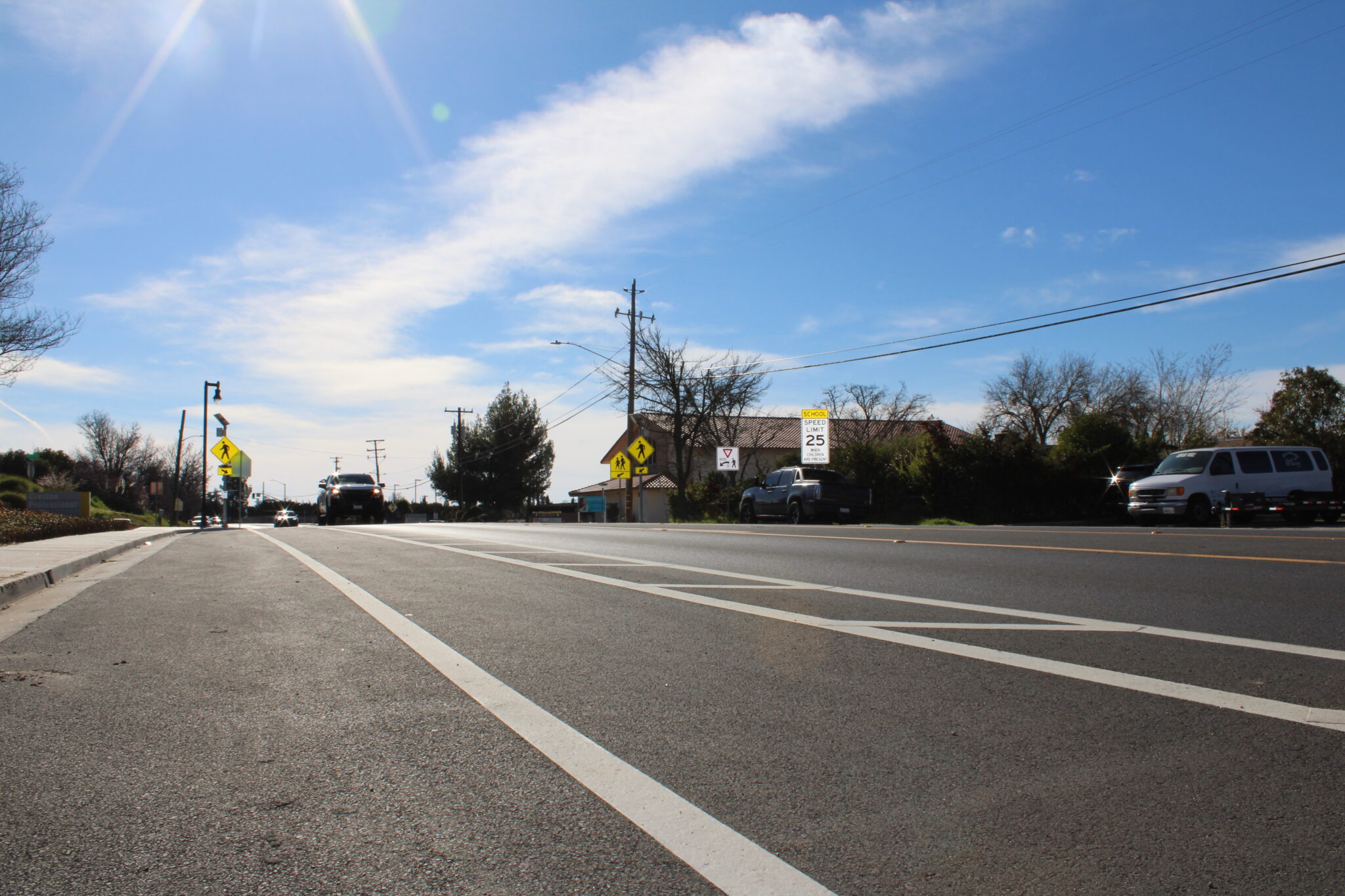 Low angle view of newly paved street with white striping and a blue sky in the background